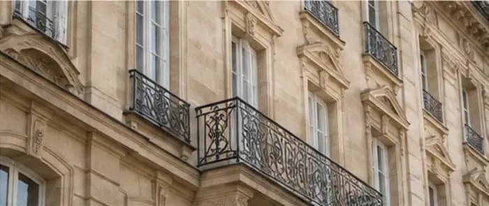 Façade en pierre claire avec balcons en ferronnerie.